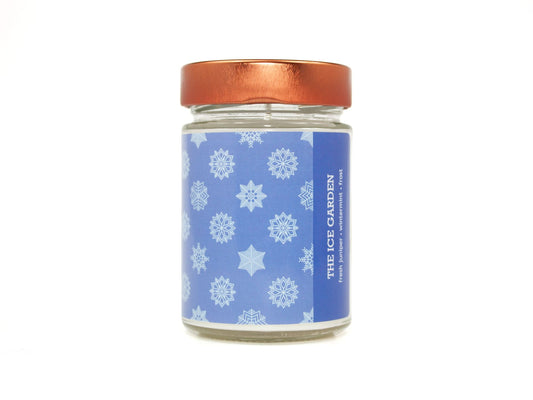 Onset & Rime juniper and mint scented candle called "The Ice Garden" in a 10 oz glass jar with copper lid. The label is blue with a pattern of lighter blue snowflakes. The text on the label is "The Ice Garden - Fresh Juniper, Wintermint, Frost".