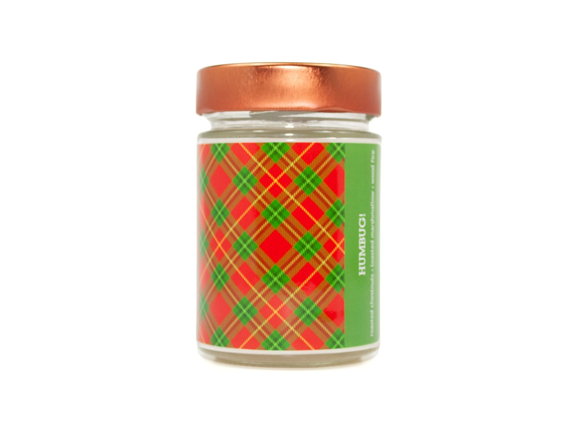 Onset & Rime sweet, smoky scented candle called "Humbug!" in a 10 oz glass jar with copper lid. The label is a red and green plaid pattern. The text on the label is "Humbug! - Roasted Chestnuts, Toasted Marshmallow, Wood Fire".