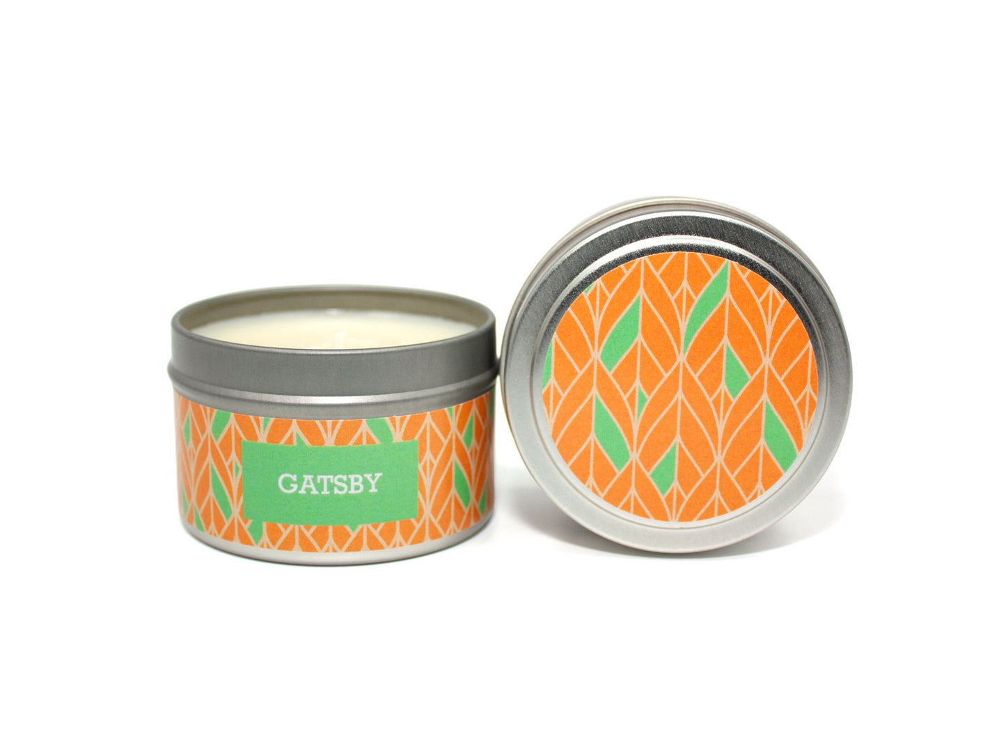 Onset & Rime champagne and satsuma scented candle called "Gatsby" in a 4 oz silver tin. The circular label on top a green and orange art deco pattern. The text on the front label is "Gatsby - Champagne, Satsuma, Lime".
