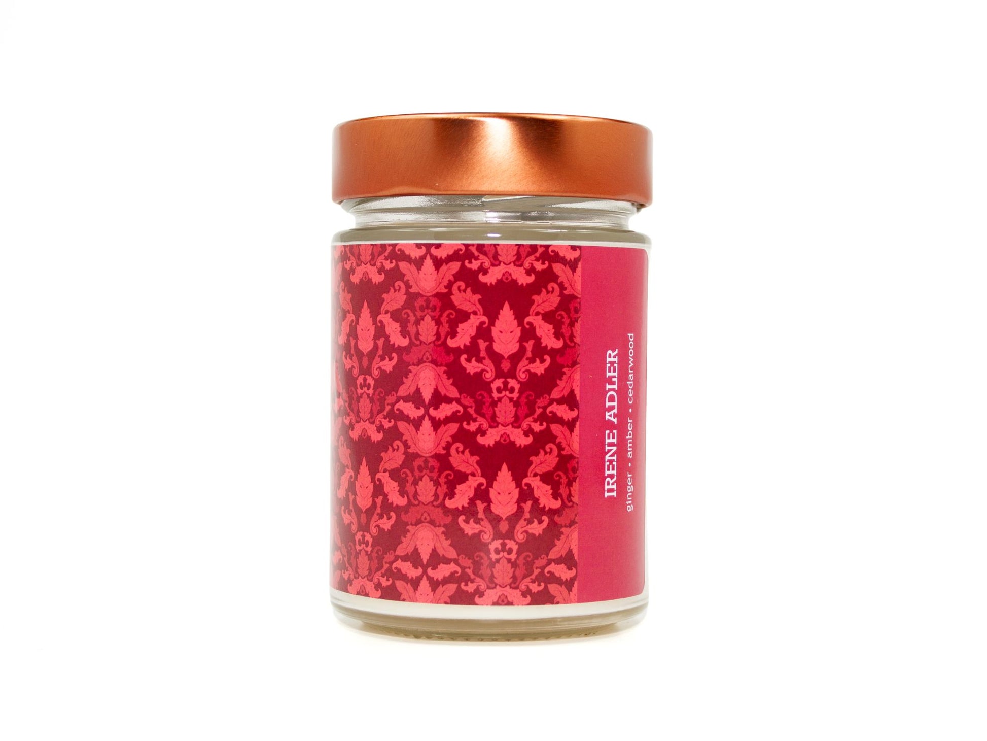 Onset & Rime ginger and amber scented candle called "Irene Adler" in a 10 oz glass jar with copper lid. The label is a deep red Victorian pattern. The text on the label is "Irene Adler - Ginger, Amber, Cedarwood".