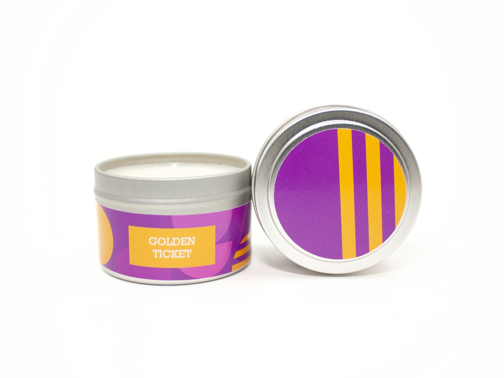 Onset & Rime chocolate bar scented candle called "Golden Ticket" in a 4 oz silver tin. The circular label on top is a geometric pattern of purple and gold half circles. The text on the front label is "Golden Ticket - Chocolate, Marshmallow Cream, Toasted Hazelnut".