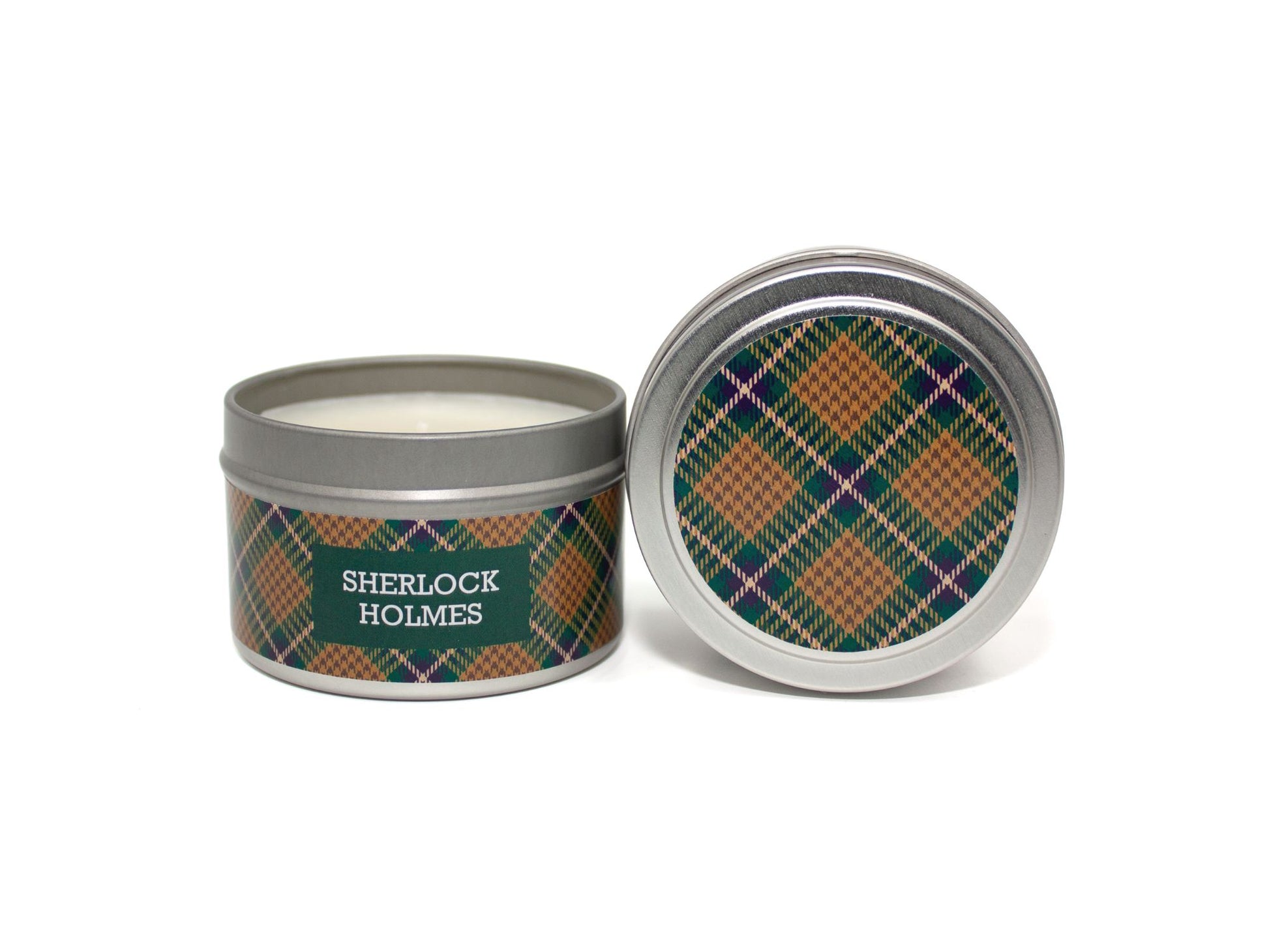 Onset & Rime woody tobacco scented candle called "Sherlock Holmes" in a 4 oz silver tin. The circular label on top is a gold and green plaid pattern. The text on the front label is "Sherlock Holmes - Cardamom, Tobacco, Teakwood".
