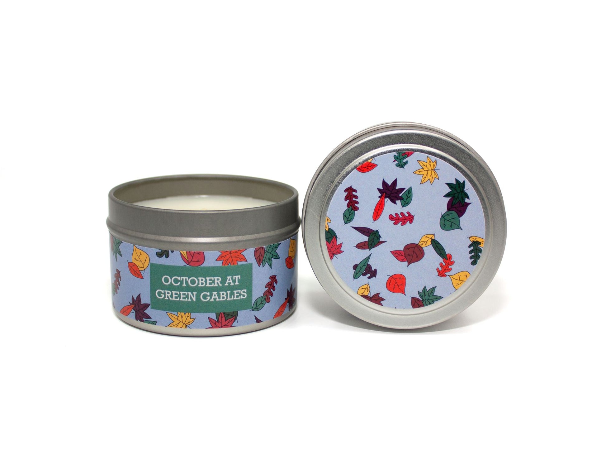 Onset & Rime pear scented candle called "October at Green Gables" in a 4 oz silver tin. The circular label on top is sky blue with a variety of autumn coloured leaves. The text on the front label is "October at Green Gables - Orchard Pear, Autumn Leaves, Birch Bark".
