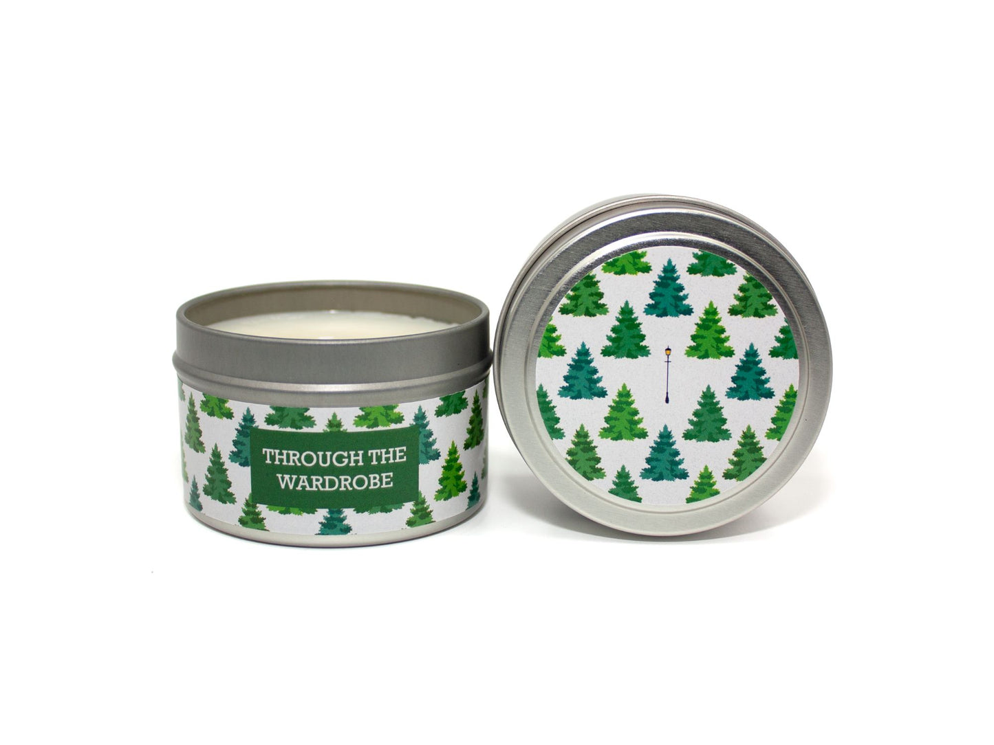 Onset & Rime balsam scented candle called "Through the Wardrobe" in a 4 oz silver tin. The circular label on top has a snow-white background with a pattern of green fir trees and a single light post. The text on the front label is "Through the Wardrobe - Balsam Fir, Cedar Boards, Swirling Snow".