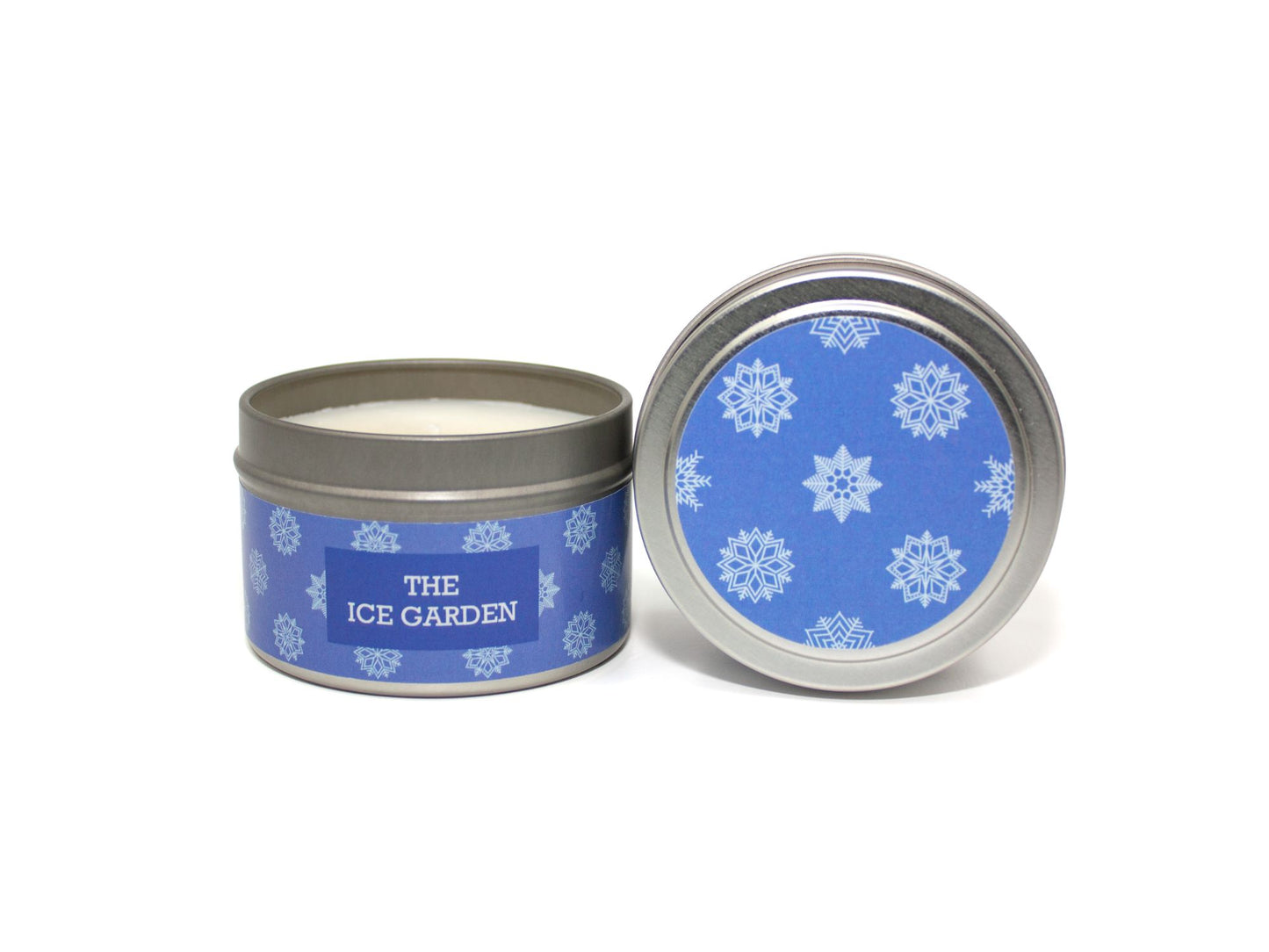 Onset & Rime juniper and mint scented candle called "The Ice Garden" in a 4 oz silver tin. The circular label on top is blue with a pattern of lighter blue snowflakes. The text on the front label is "The Ice Garden - Fresh Juniper, Wintermint, Frost".