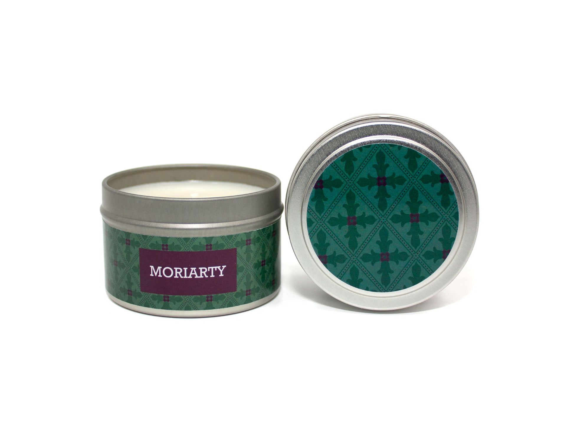 Onset & Rime fig and vetiver scented candle called "Moriarty" in a 4 oz silver tin. The circular label on top is a deep green gothic-style pattern. The text on the front label is "Moriarty - Fig, Vetiver, Suede".