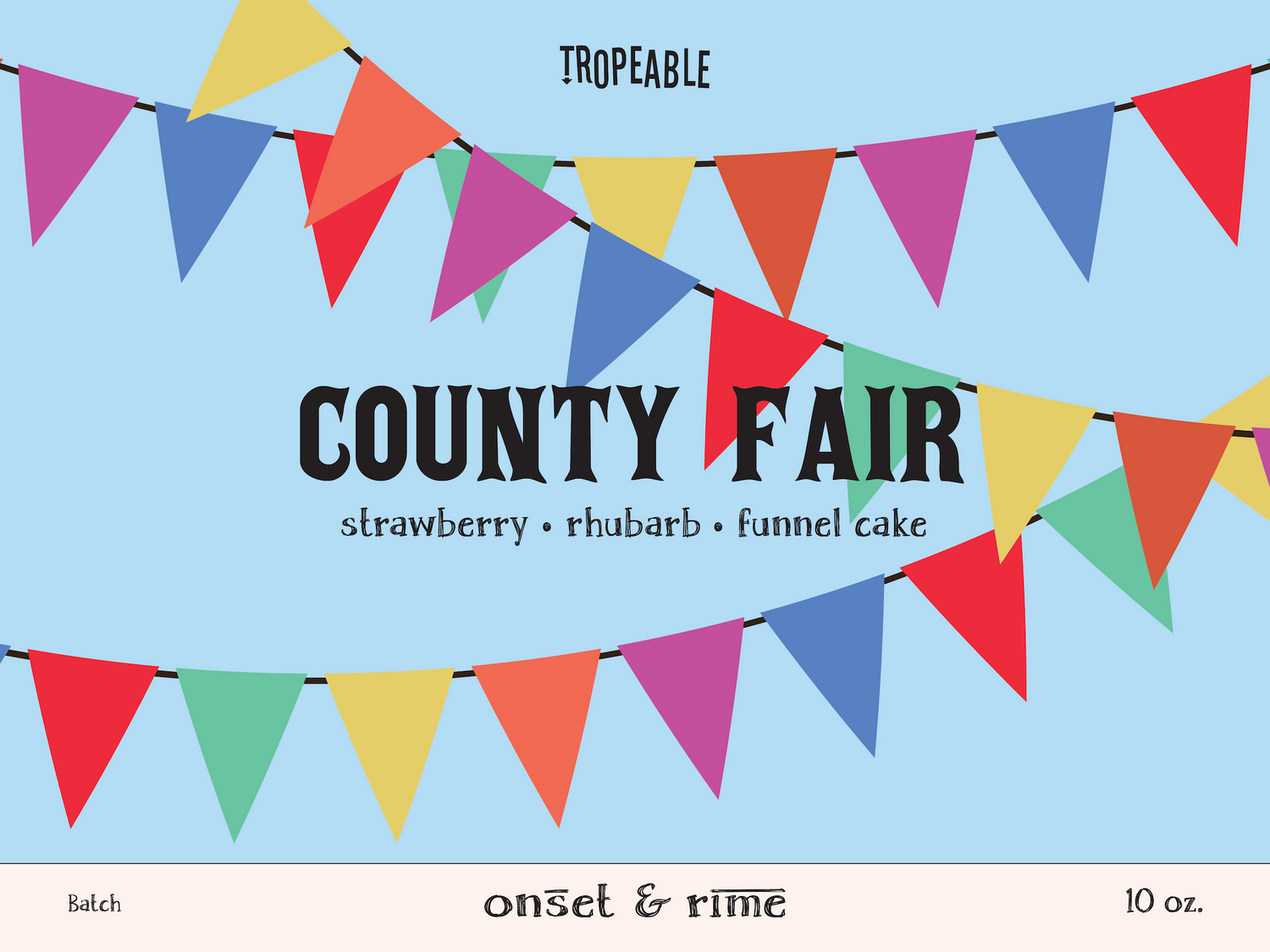 A close up view of the label for the Onset & Rime strawberry rhubarb funnel cake scented candle called "County Fair". The label has a light blue background with colourful pennant banners. The text on the label is "County Fair - Strawberry, Rhubarb, Funnel Cake".
