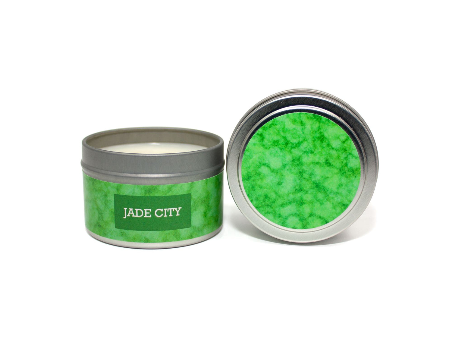 Onset & Rime pomelo, green tea and mint scented candle called "Jade City" in a 4 oz silver tin. The circular label on top is cool green with a lighter green mottling. The text on the front label is "Jade City - Pomelo, Green Tea, Mint".