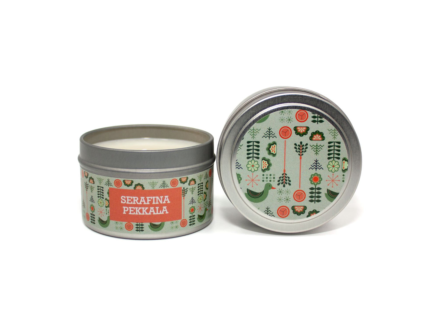 Onset & Rime floral pine scented candle called "Serafina Pekkala" in a 4 oz silver tin. The circular label on top is pale green with a pattern of pine branches, compasses, a goose and more arctic symbols. The text on the front label is "Serafina Pekkala - Geranium, Neroli, Cloud Pine, Arctic Air".